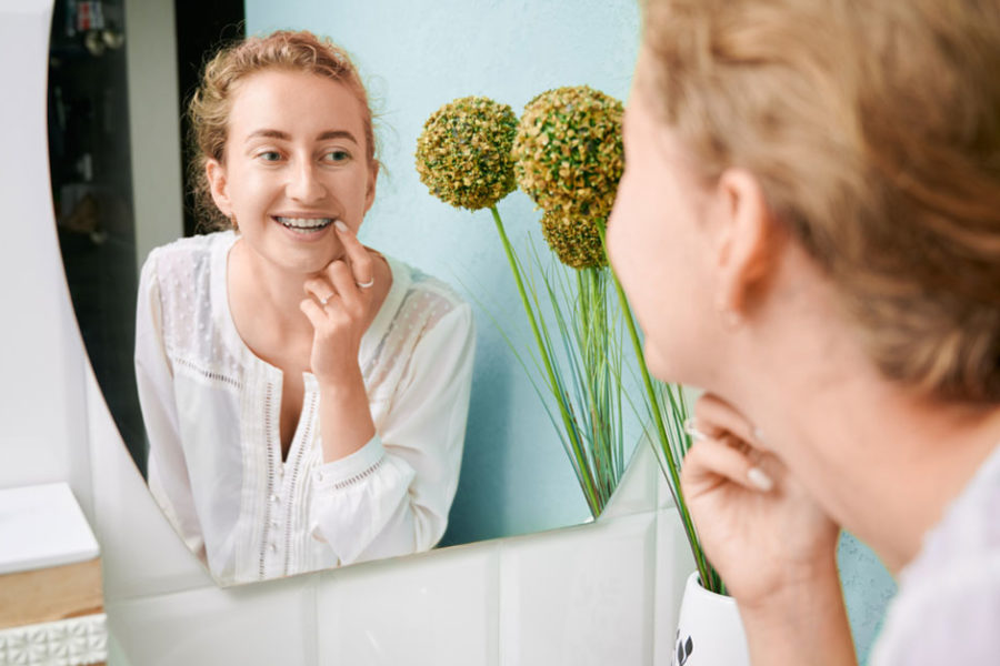 teenage girl looking at braces in mirror