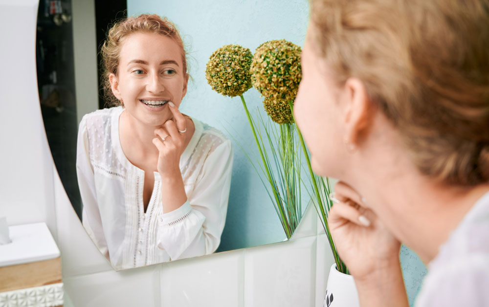 teenage girl looking at braces in mirror