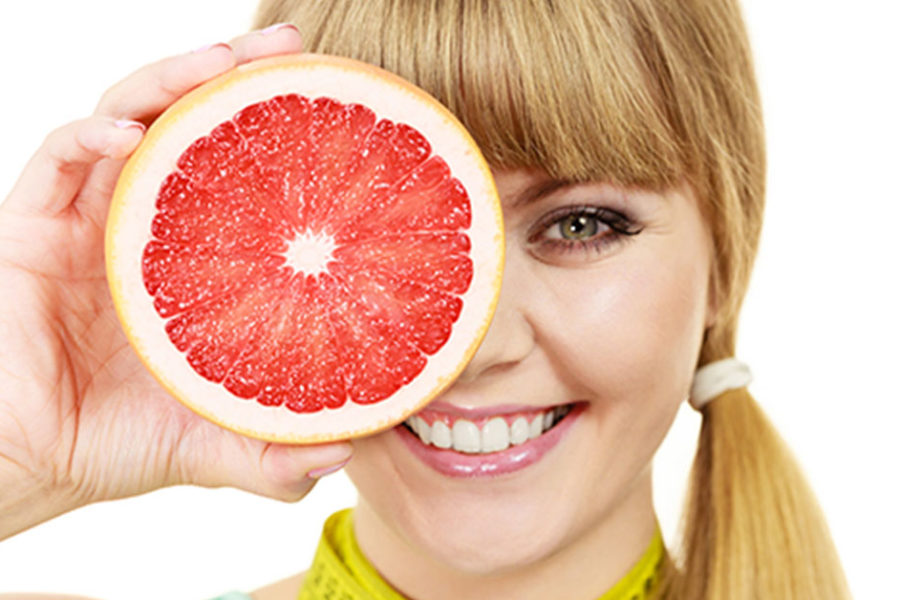 girl holding grapefruit smiling