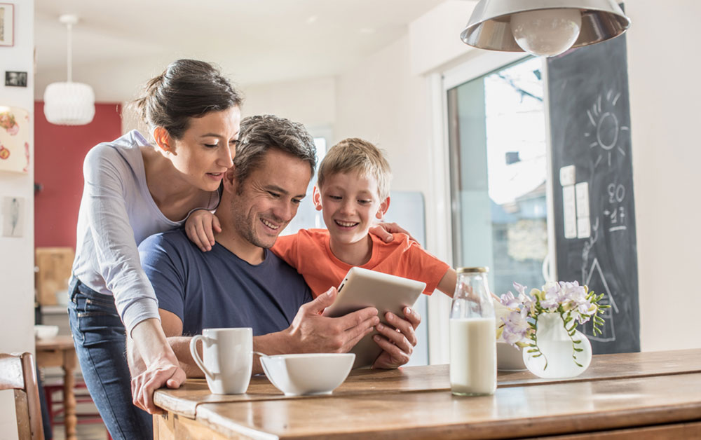 family looking at tablet smiling